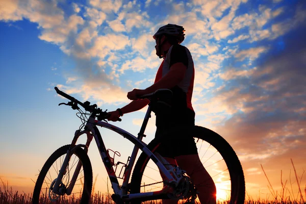 Sylwetka rowerzystę i rowerów na tle zachodu słońca. — Zdjęcie stockowe