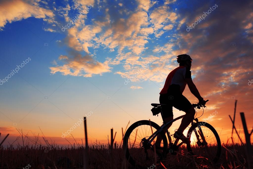 Silhouette of a biker and bicycle on sunset background.