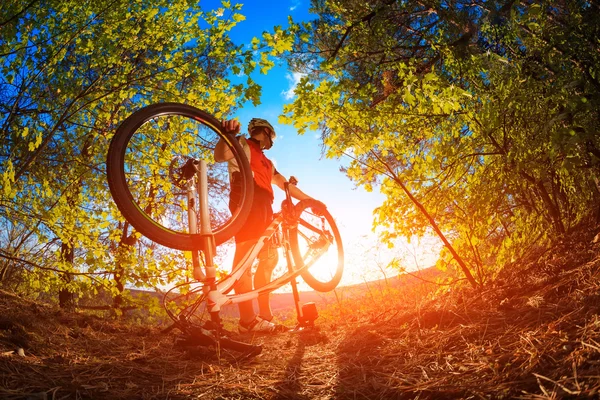 Человек-велосипедист чинит велосипед на фоне голубого неба — стоковое фото