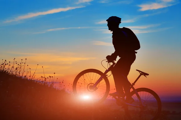 Silhouette di un motociclista e bicicletta sullo sfondo del tramonto . — Foto Stock