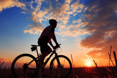Silhouette bir motorcu ve gün batımı arka plan üzerinde bisiklet.