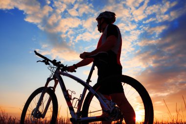 Silhouette bir motorcu ve gün batımı arka plan üzerinde bisiklet.