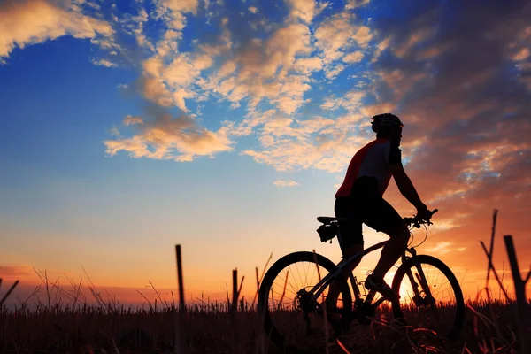 バイクに乗る人、夕日を背景に自転車のシルエット. — ストック写真
