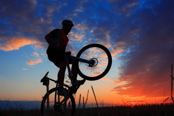 Sylwetka rowerzystę i rowerów na tle zachodu słońca. — Zdjęcie stockowe