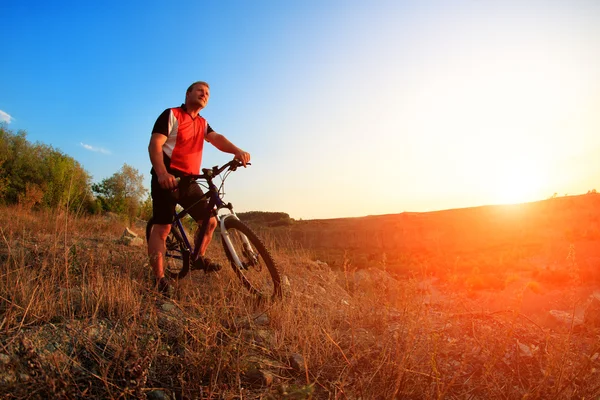 Велосипедист на гірському велосипеді їде одноколійною трасою на сході сонця — стокове фото