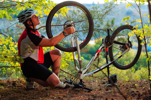 Junger Mann repariert Mountainbike im Wald — Stockfoto