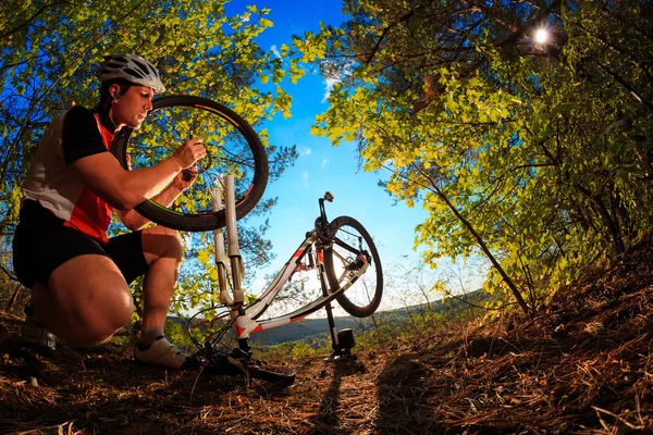 Fahrradfahrer repariert Fahrrad bei blauem Himmel — Stockfoto
