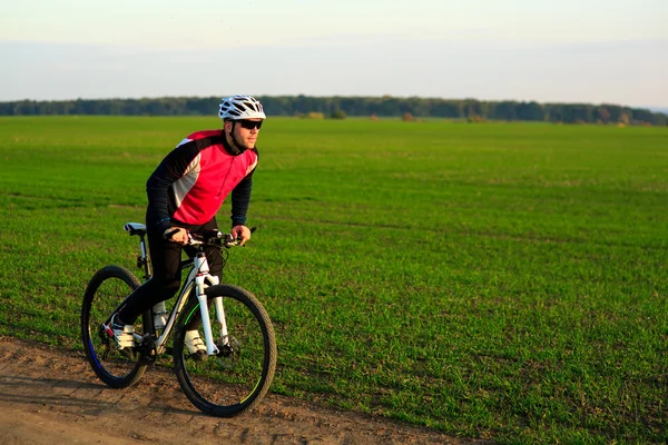 Ciclista joven adulto montando bicicleta de montaña en el campo — Foto de Stock