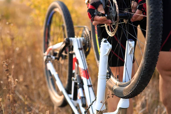 Joven reparando bicicleta de montaña en el bosque — Foto de Stock