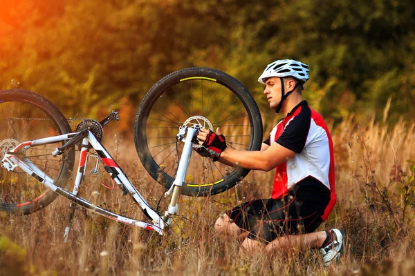 Hombre ciclista reparando una bicicleta contra la naturaleza verde —  Fotos de Stock