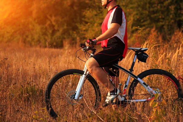 Muž cyklista cyklistika na venkovské cestě při západu slunce — Stock fotografie