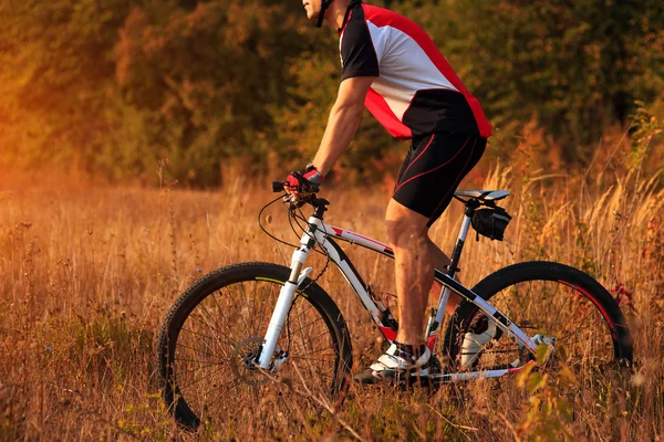 Cyklist man cykla på en lantlig väg under solnedgången — Stockfoto