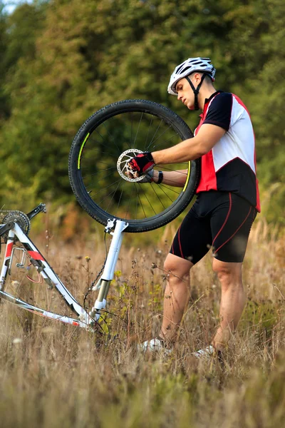 Чоловік ремонтує свій гірський велосипед — стокове фото