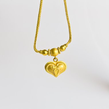 beyaz zemin üzerine altın kolye