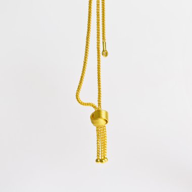 beyaz zemin üzerine altın kolye.