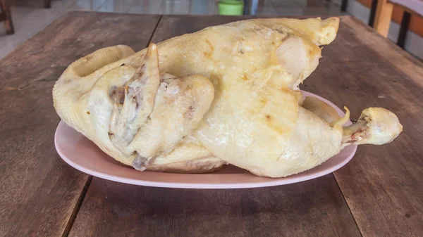 Pollo cocido en un plato rosa sobre una mesa de madera . — Foto de Stock