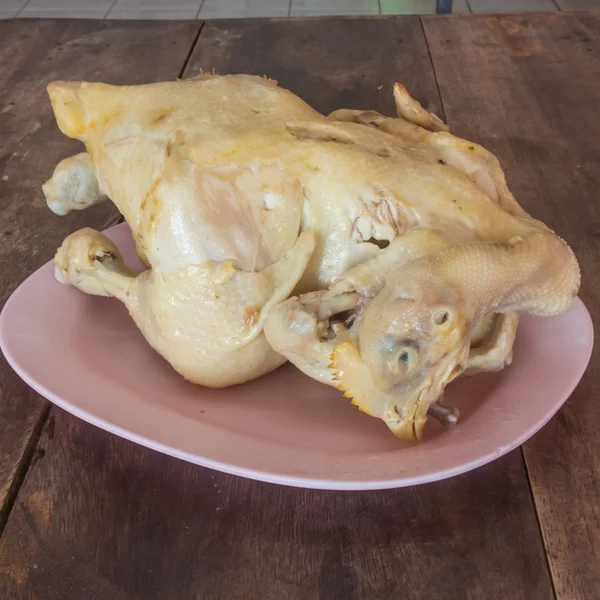 Ahşap bir masa pembe bir tabağa pişmiş tavuk.