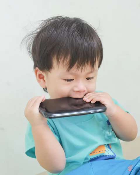 Boy bites a smartphone. — Stock Photo, Image