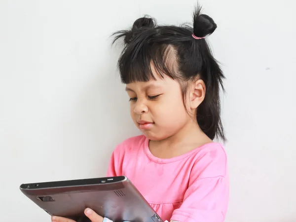 Young cheerful girl is using tablet while sitting at table — Stock Photo, Image