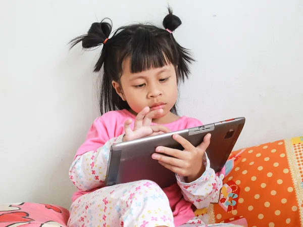 Joven chica alegre está utilizando la tableta mientras está sentado en la mesa — Foto de Stock