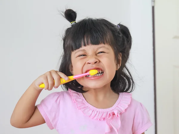 Girl smiling while brushing her teeth — Stock Photo, Image