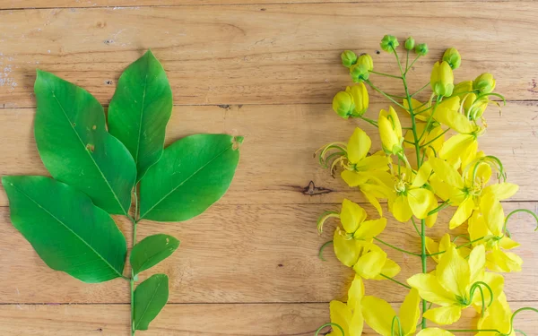 Golden Flower or Cassia Fistula and leaf on wooden background — Stock Photo, Image