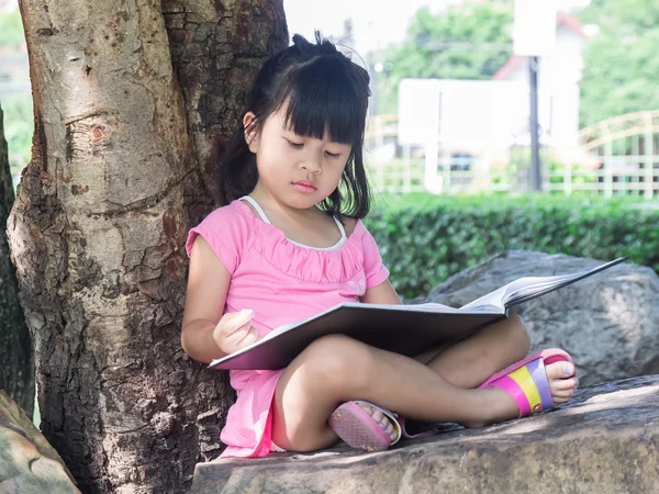 Retrato ao ar livre de uma menina bonita lendo um livro — Fotografia de Stock