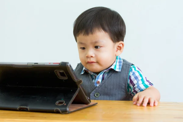 Portrait of child on table in a game on a digital tablet — Stock Photo, Image