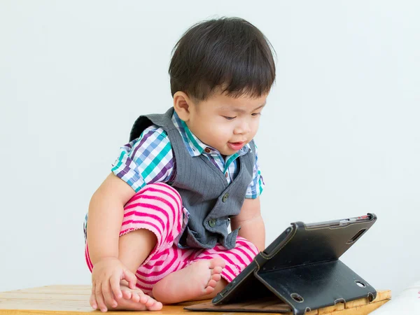 Portrait of a child sitting on table in a game on a digital tablet — Stock Photo, Image