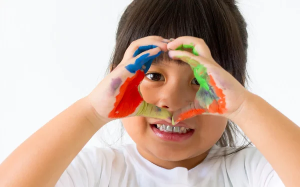 Niña con las manos en la pintura y la mano hacer corazón en blanco — Foto de Stock