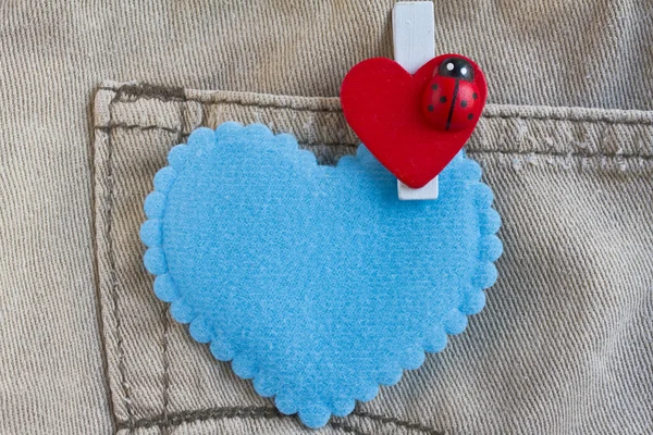 Red heart clothes peg and blue heart on jeans background — Stock Photo, Image