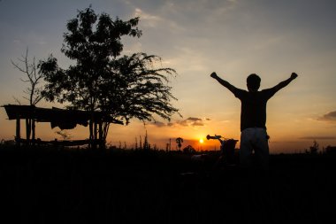 Siluet bir adamın elini kaldırdı ve güneşe bakarak durdu