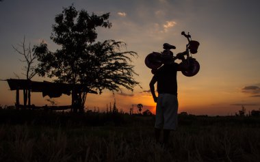 günbatımı arayan adam Asansör bisiklet bir siluet standları.