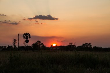 Manzara, bir alanda gün batımı ve ev
