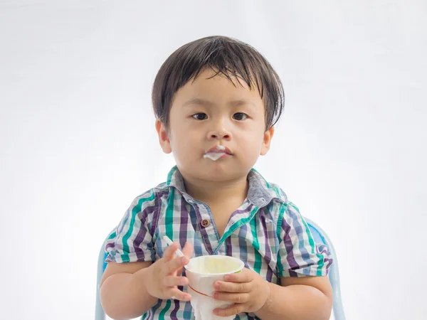Retrato do menino comendo iogurte no fundo branco — Fotografia de Stock