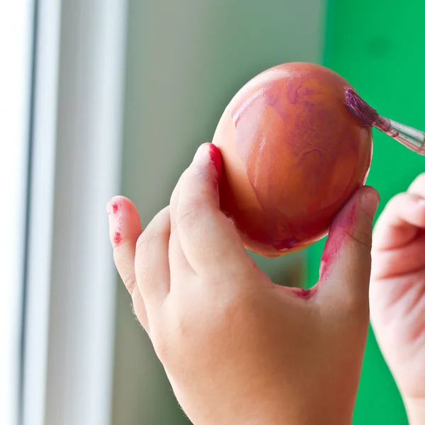 Menina segurando ovo e pintá-lo com cor cinza — Fotografia de Stock