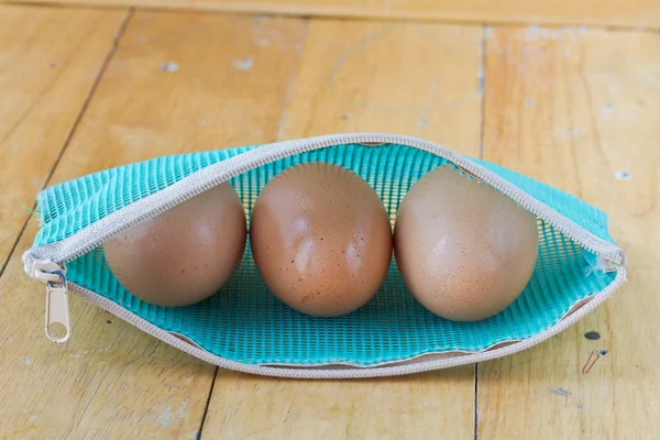 Ägg i en dragkedja väska på träbord — Stockfoto