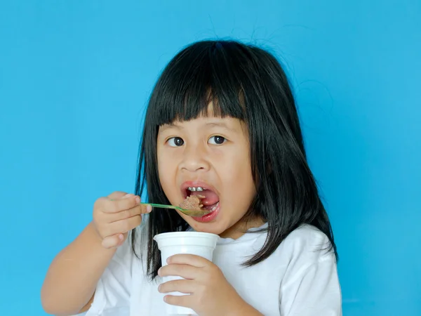 青の背景にアイスクリームを食べる女子高生 — ストック写真