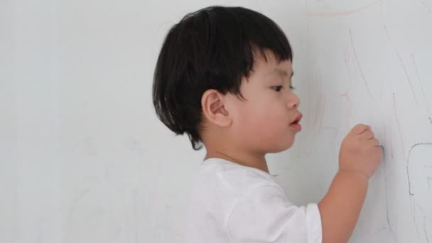 Niño pequeño escribiendo sobre fondo de pared — Vídeos de Stock