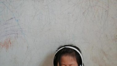 Kız müzik dinliyor. Desen duvarda oturan çocuk. Ona telefon eller.