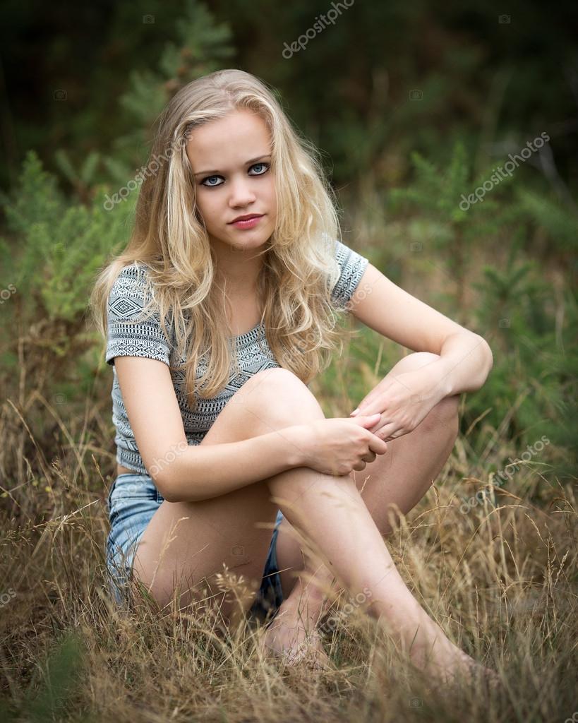 Довольно блондинка подросток сидя в траве — Стоковое фото © Heijo 103692060