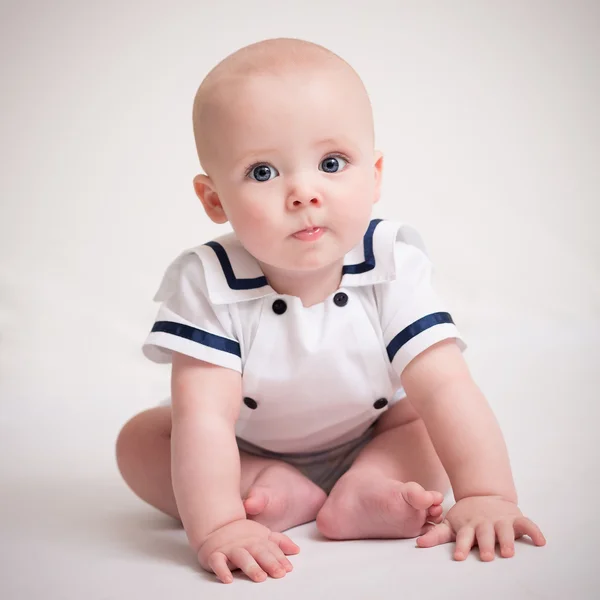 Baby Boy sitter på golvet i sjöman kostym Royaltyfria Stockfoton