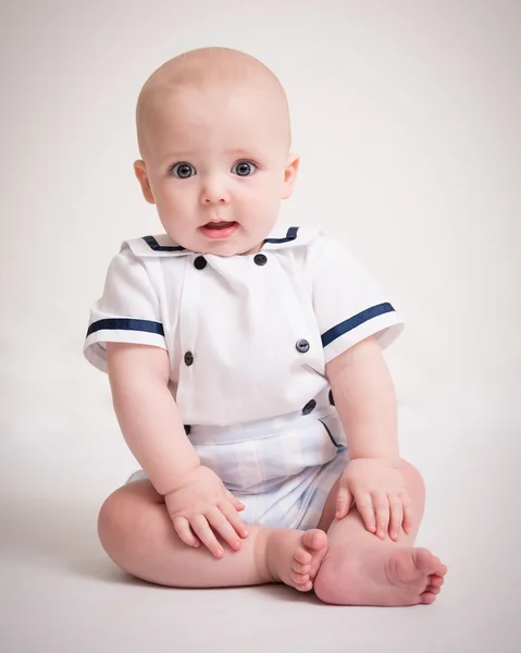 Baby Boy sitter på golvet i sjöman kostym Stockbild