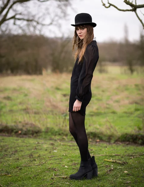 Vakker ung kvinne kledd i svart, bærende bowlerhatt – stockfoto