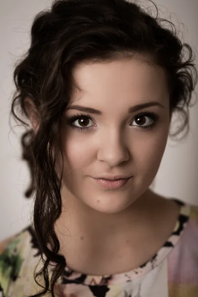 Porträtt av en vacker flicka med bruna ögon mot en grå rygg — Stockfoto