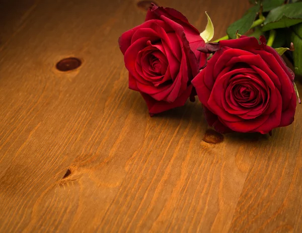 Dos rosas rojas sobre madera marrón — Foto de Stock