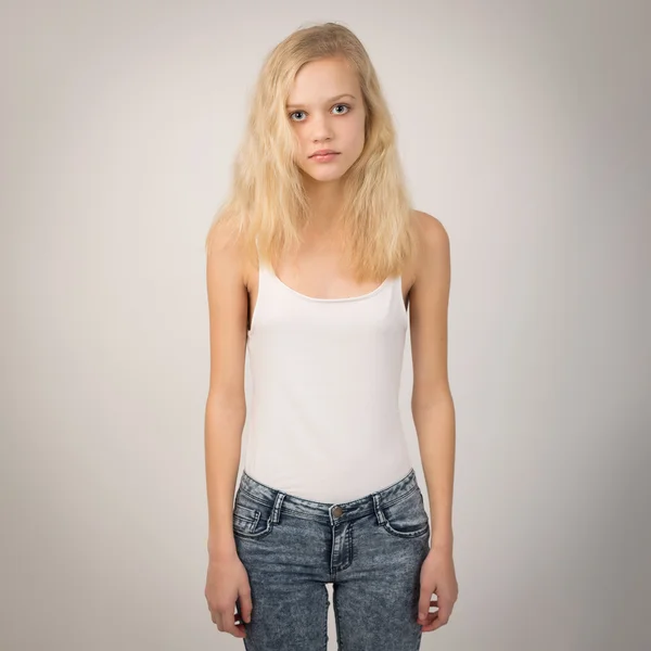 Blond Serious Girl Standing Straight Wearing A White Top Stockbild