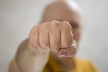 Ön planda bir adam yumruğu, arka planda saldırgan bir adam odak dışı.