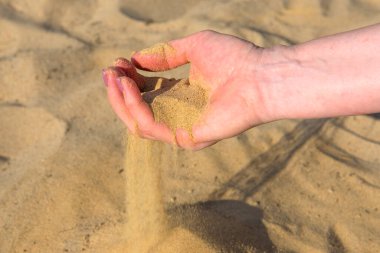 Katlanmış avuçlardan kum bir kadının elinin parmaklarından akar.