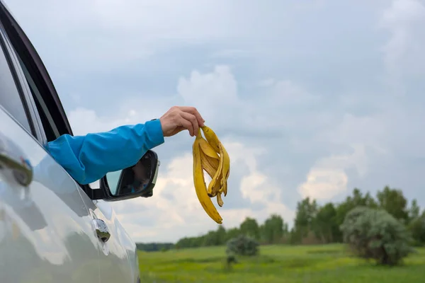 Een Vrouwenhand Gooit Bananenschillen Uit Het Autoraam — Stockfoto